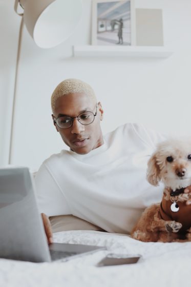 Man working from home on bed with dog