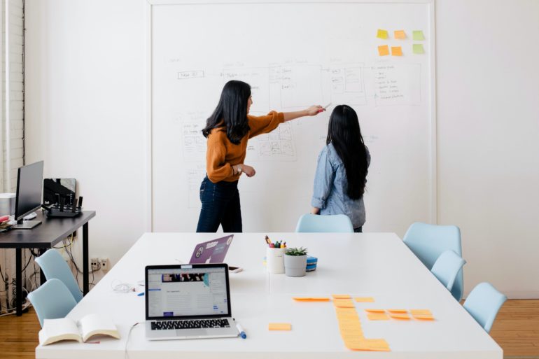 Women in front of office whiteboard