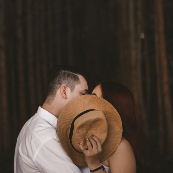 Couple kissing, hidden behind hat